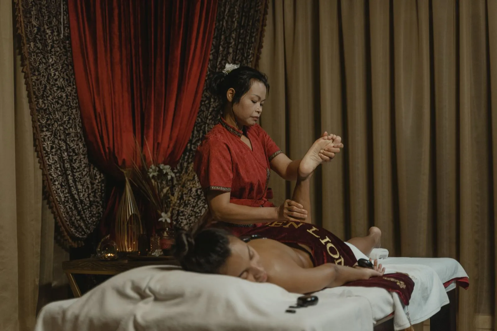 A woman receives a therapeutic massage from a professional masseuse in a calming spa environment.